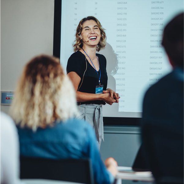 Smiling woman in front of a screen as she presents